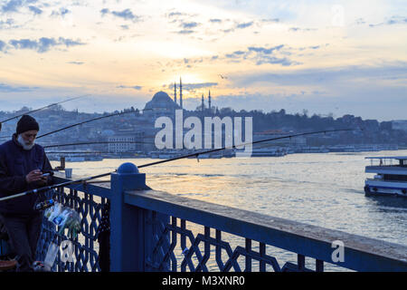 Al Ponte di Galata a Istanbul- gennaio 8 2018: persone di pesca sul ponte Galata con la moschea di Suleymaniye background durante il tramonto, Istanbul. Foto Stock