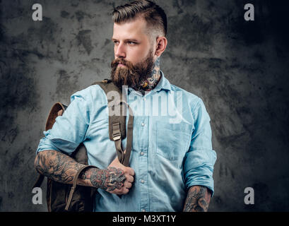 Un uomo con tatuaggi sulle sue braccia e collo con zaino sulla sua bac Foto Stock