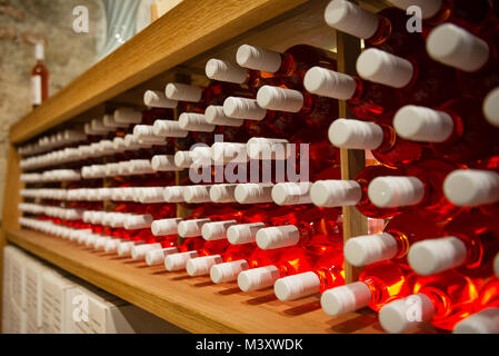 Bottiglie di vino rosa sul ripiano in cantina Foto Stock