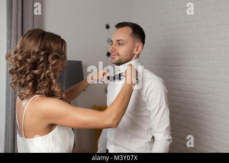 Correzioni per la sposa il filtro bow tie su groom s collo mentre stanno vestito in camicia bianca Foto Stock
