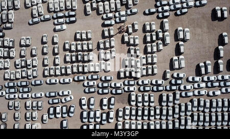 Nuove auto coperto di protezione fogli bianco parcheggiato in una piattaforma di contenimento - riprese aeree Foto Stock