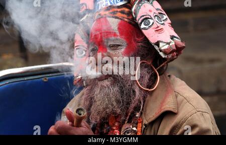 Kathmandu, Nepal. Xiii Febbraio, 2018. Un uomo santo (sadhu) nella religione indù fuma durante il festival indù di Maha Shivaratri presso il tempio di Pashupatinath a Kathmandu, Nepal, Feb 13, 2018. Maha Shivaratri è un festival indù che si celebra ogni anno nella riverenza ofLord Shiva. Credito: Sunil Sharma/Xinhua/Alamy Live News Foto Stock