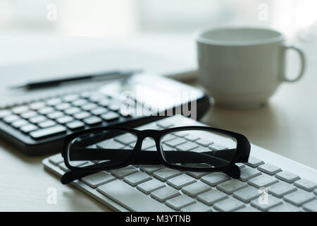 Close up di bicchieri e computer business sul posto di lavoro posto di lavoro in ufficio Foto Stock
