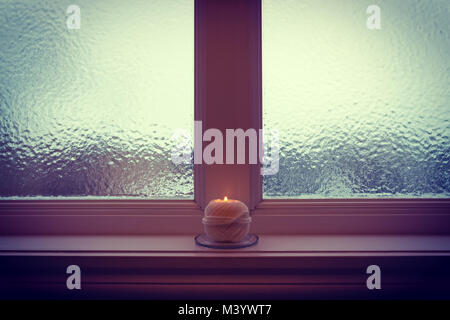 Candela che brucia e vetro smerigliato in Twilight. Accogliente sera d'inverno. Foto Stock