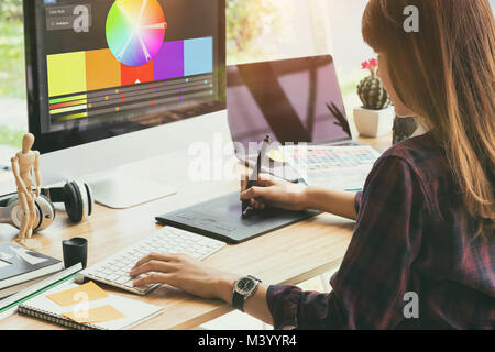 Graphic designer che lavora su creative desk computer mentre con tavoletta grafica alla scrivania in ufficio Foto Stock