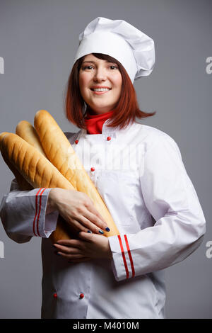 Immagine di donna cucinare in tunica bianca e cappuccio con pani Foto Stock