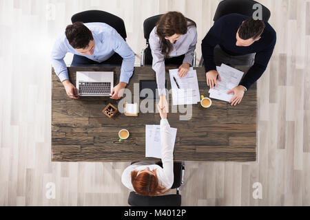 Gruppo di Corporate assunzione ufficiali agitando la mano con il candidato è arrivato per il colloquio Foto Stock