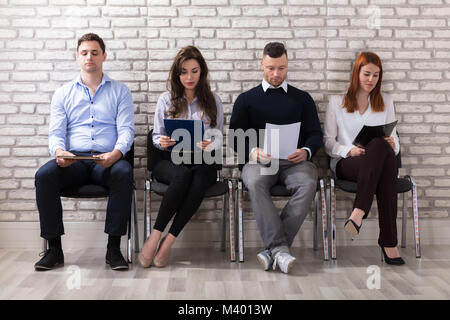 Gruppo di persone seduti su una sedia in attesa per il colloquio di lavoro in ufficio Foto Stock