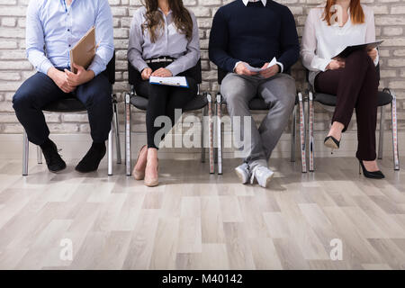 Close-up di gente di affari seduti su una sedia in attesa per il colloquio di lavoro in ufficio Foto Stock