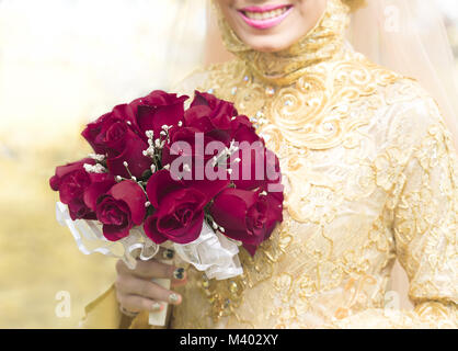 Sposa musulmana tenendo un mazzo di nozze in mano un mazzo di rose rosse fiore Foto Stock