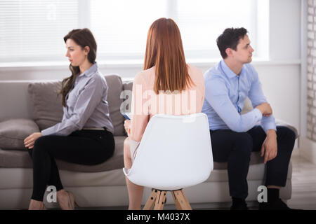 Vista posteriore di psicologo femmina seduta con giovani orinato giovane Foto Stock