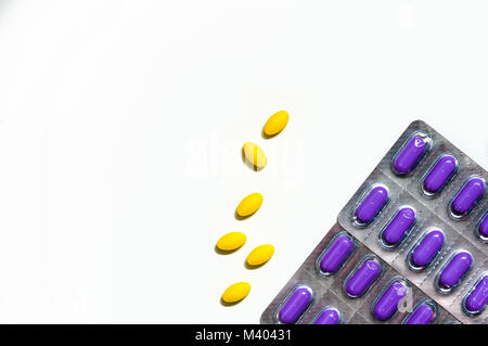 Macro shot di giallo compressa ovale pillole su sfondo bianco e viola caplet pillole in confezione blister. Da lieve a moderata la gestione del dolore. Pain Killer med Foto Stock