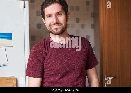 Contenuto uomo bello in piedi nella sua cucina a casa Foto Stock