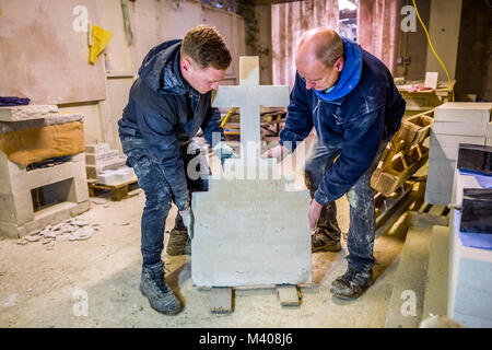 Lettera-carver Ollie Laughton, sinistra e restauratore di Michael Cook, a destra dal Tilley scalpellini del di Brighton, East Sussex, ispezionare la lapide di Tom Foto Stock