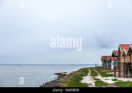 Gli allevatori di ostriche di capanne vicino all'Oceano Atlantico durante un nuvoloso pomeriggio piovoso sulla baia di Arachon (Bassin d'Arcachon) nella parte sud-ovest della Francia, in Aquitaine. Un Foto Stock