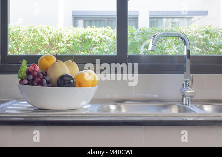 La frutta in una ciotola accanto al lavello in cucina Foto Stock