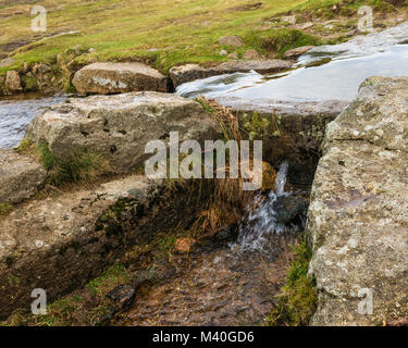 "Bullseye pietra" su Grimstone e Sortridge Leat, Parco Nazionale di Dartmoor. Il foro nella pietra regola il flusso di acqua in un canale laterale. Foto Stock