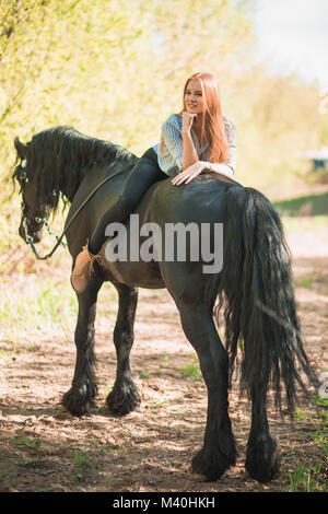 Pilota giovane ragazza con i capelli lunghi che giace sul collo del cavallo Foto Stock