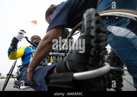Shundra Johnson aiuta a fissare il marito Coast Guard Lt. Sancho Johnson in un ciclo di mano durante la Marina il guerriero ferito training camp per il 2015 DoD Warrior giochi al Ventura County Naval Station Port Hueneme in Oxnard, ca. Il 31 maggio 2015. (DoD News foto da EJ Hersom) 150530-D-DB155-777 dal DoD Notizie Foto Foto Stock