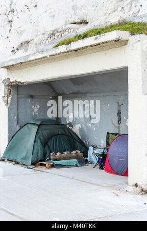 Una persona senza dimora ha eretto una tenda in un rifugio in disuso sul lungomare a Ramsgate, appena sotto le scogliere sul lungomare. Foto Stock