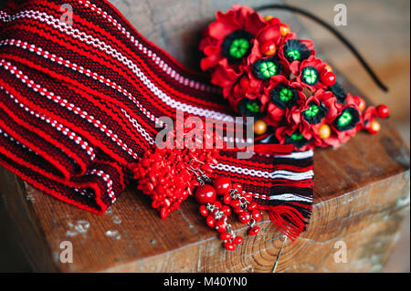 Ucraino nazionale etnica accessori fatti a mano su un sfondo di legno. Ceramica rossa orecchini e bracciale, Donna Accessori per capelli con rosso popp polimerico Foto Stock