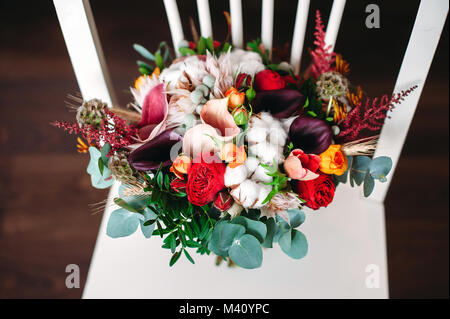 Bouquet di nozze in boho chic e di stile rustico con cotone, viola callas fiori, rose rosse, foglie di eucalipto. Vista superiore Foto Stock