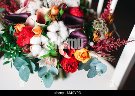 Bouquet di nozze in boho chic e di stile rustico con cotone, viola callas fiori, rose rosse, foglie di eucalipto. Vista superiore Foto Stock