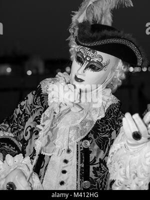 Maschio goer di carnevale in costume tradizionale e la maschera in piedi con la schiena al Canal Grande e gondole e San Giorgio in background Foto Stock