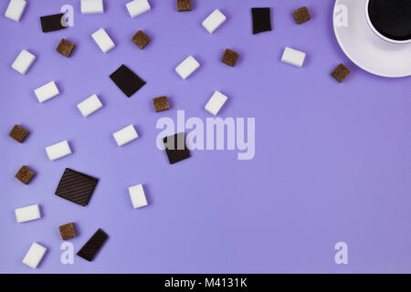 White tazza di caffè, marrone e bianco cubetti di zucchero e cioccolato prieces su sfondo viola. Vista superiore Foto Stock