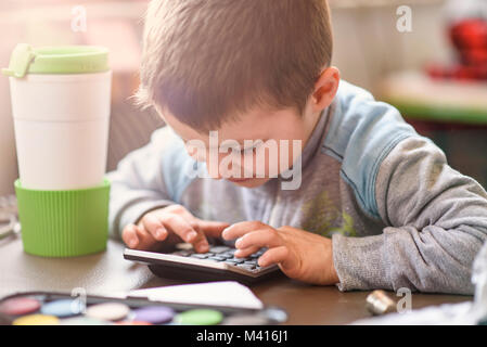 Piccolo Grazioso baby boy utilizzando una calcolatrice Foto Stock