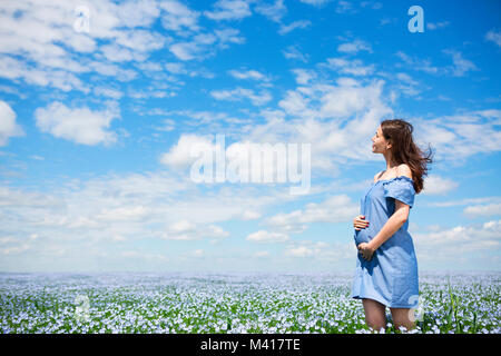 Ritratto di una giovane bella donna incinta nel campo di lino Foto Stock