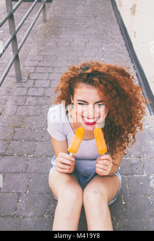 Redhead giovane donna mangiare gelati in estate Foto Stock