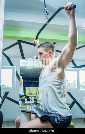 Spalla tirare verso il basso la macchina. Uomo Fitness lavoro lat pulldown di formazione presso la palestra. La parte superiore del corpo la forza per esercitare la parte superiore della schiena. Foto Stock