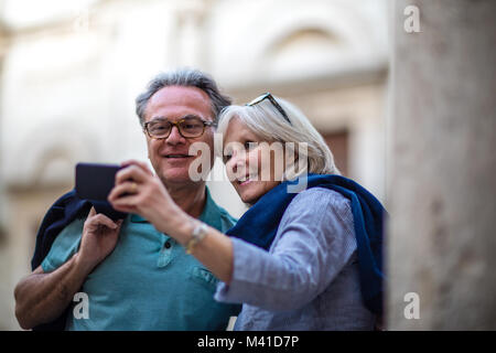 Coppia senior in vacanza di scattare una foto a un sito turistico Foto Stock
