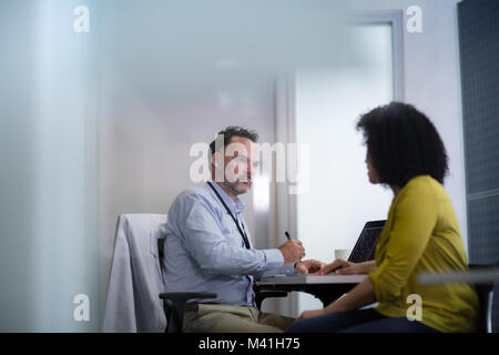 Voce maschile medico prendendo nota dei sintomi del paziente Foto Stock