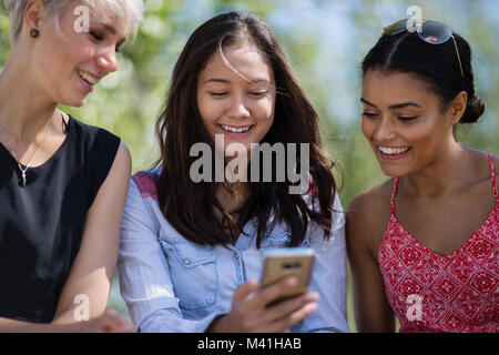 Amici di sesso femminile guardando smartphone Foto Stock