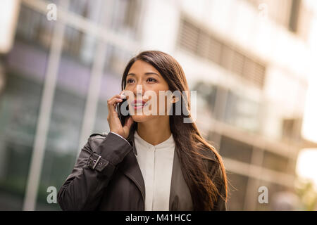 Donna che utilizza smartphone passeggiate in città Foto Stock