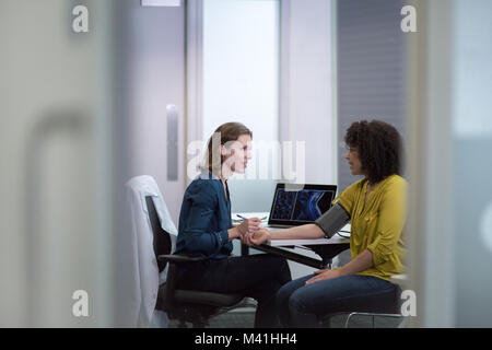 Donne medico tenendo a pazienti con pressione sanguigna Foto Stock