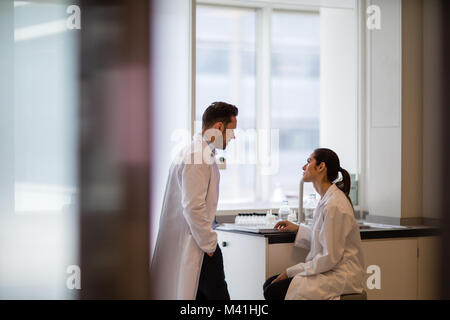 Donna scienziato discutere i risultati di esperimento con il collega di sesso maschile Foto Stock