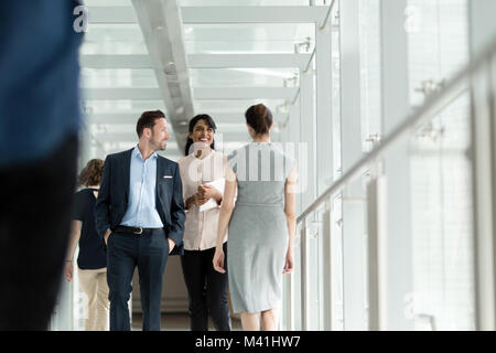 Colleghi di lavoro a piedi attraverso ufficio indaffarato corridoio Foto Stock