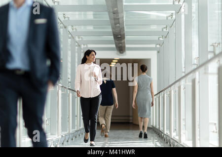 Femmina executive business a piedi attraverso ufficio indaffarato corridoio Foto Stock