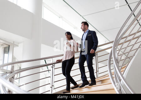 Colleghi di lavoro scendendo la scala a chiocciola Foto Stock