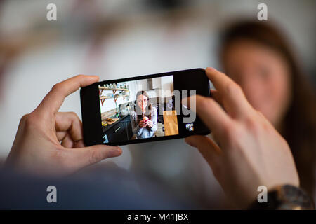 Tenendo lo smartphone foto di donna holding tortina con candela Foto Stock
