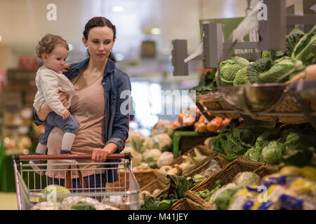 Madre e figlia acquistare verdure nel negozio di alimentari Foto Stock