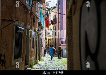 Una donna cammina attraverso un vicolo di Alfama a Lisbona, Portogallo. Foto Stock