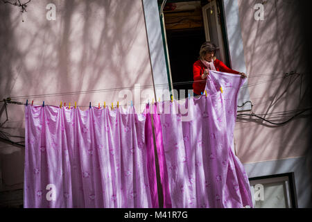 Una donna si blocca servizio lavanderia sul suo balcone a Lisbona, Portogallo. Foto Stock