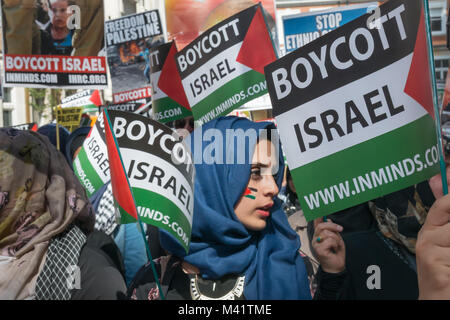 Una donna in un velo di colore blu con una bandiera palestinese dipinta sulla sua guancia è circondato da "Boicottare Israele" bandiere palestinese come ella attende all'inizio di Al Quds giorno marzo a Londra. Foto Stock