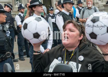 Paula Peters di DPAC detiene due palloni da calcio con i messaggi per la governent nella parte anteriore della polizia a Downing St presso le persone disabili contro i tagli "Balls al bilancio" protesta. Foto Stock