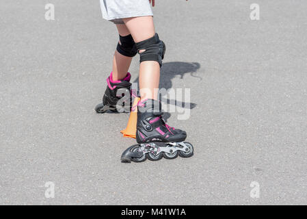 Bambina facendo andare in rollerblade in strada Foto Stock