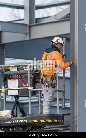 Operaio in un cherry picker piattaforma di lavoro su un edificio sito in costruzione nel Regno Unito. Foto Stock